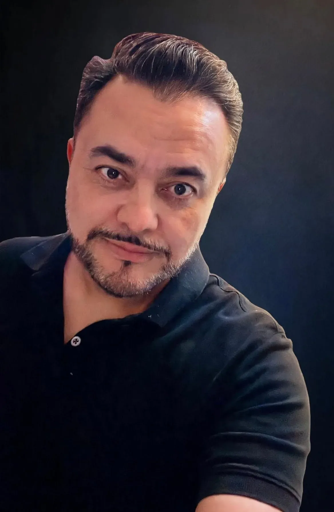 Studio portrait of Arturo Ordorika, dark jacket against a teal background