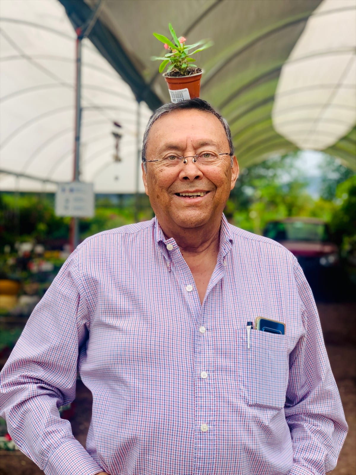 El Capitán José Arturo Zepeda sonriendo en un vivero, con una maceta pequeña en la cabeza