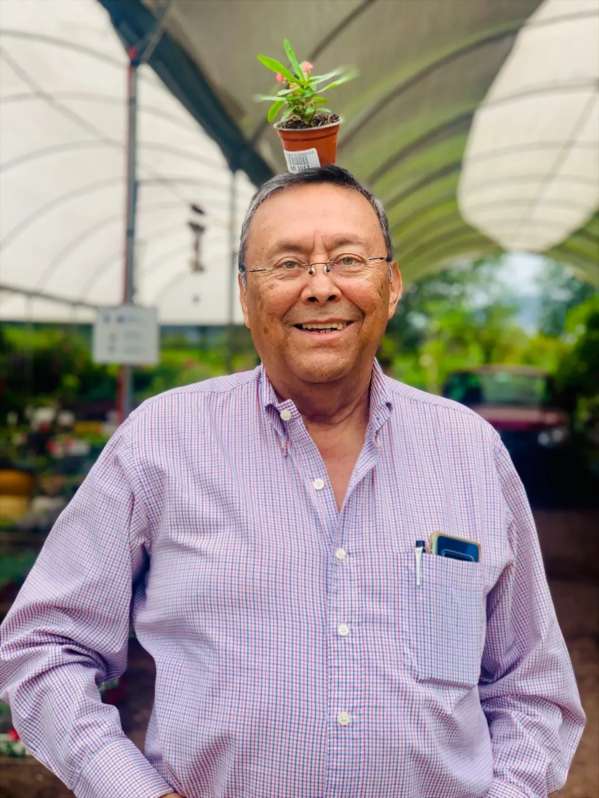 Captain José Arturo Zepeda smiling in a plant nursery, a small flowerpot on his head