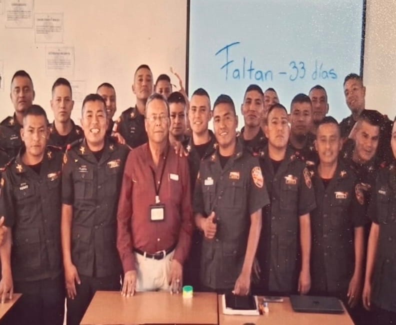 El Capitán Zepeda, de camisa vino, al centro de un grupo grande de sargentos en un aula; en el pizarrón dice «Faltan 33 días»